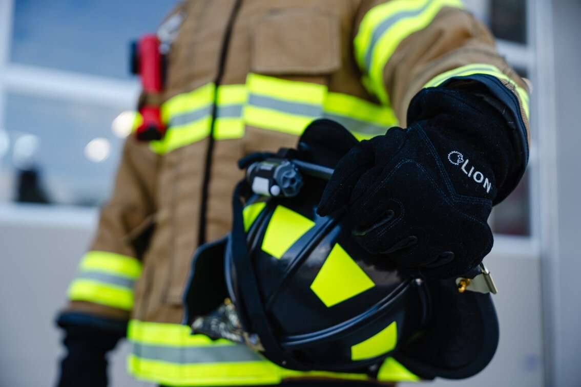 firefighter holding helmet wearing jacket and gear